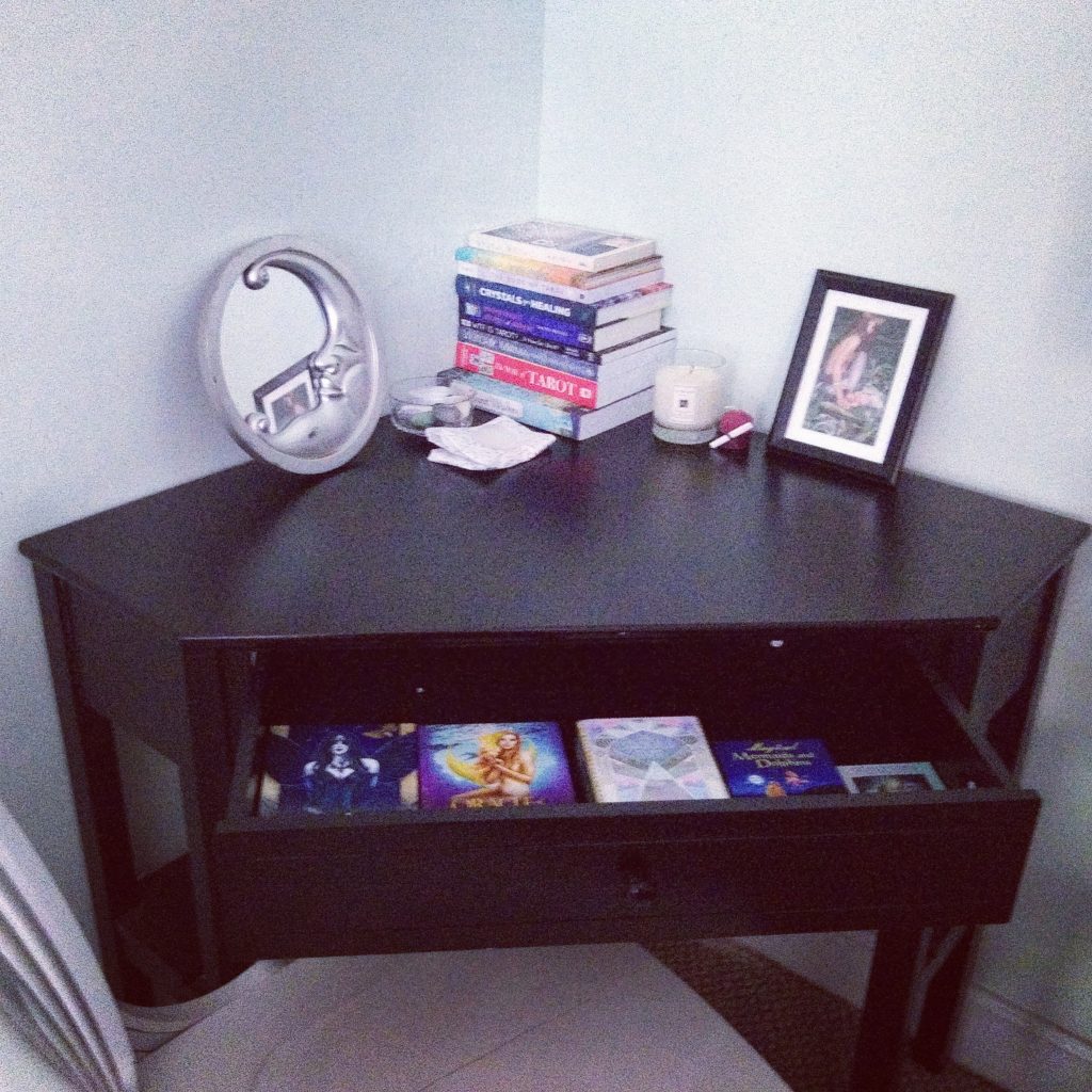 Black corner desk with books, crystals, and tarot and oracle decks